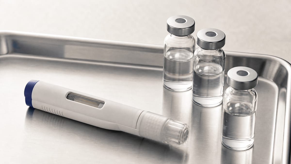 Close-up of a subcutaneous auto-injector pen and glass medicine vials on a clinical tray, representing a pharmaceutical therapy.