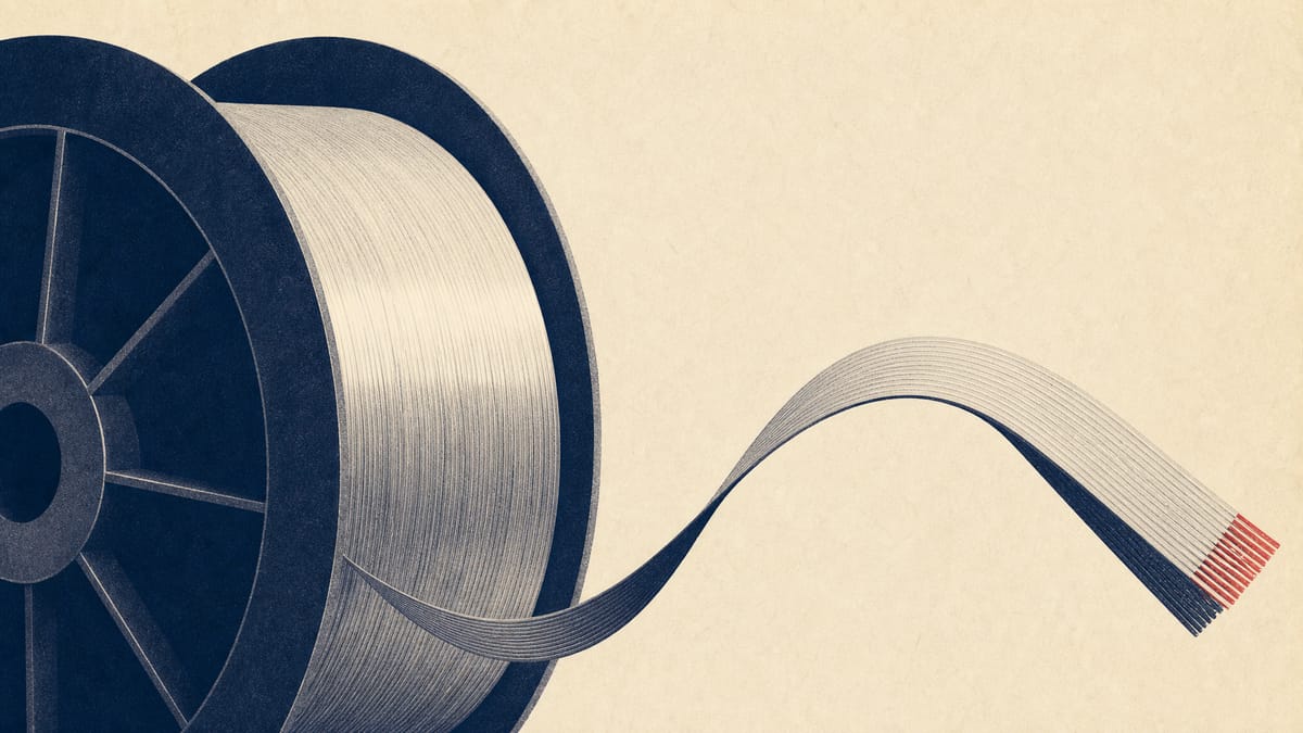 Spools of optical fiber and ribbon cable on an industrial production line, representing Furukawa Electric's capacity expansion.