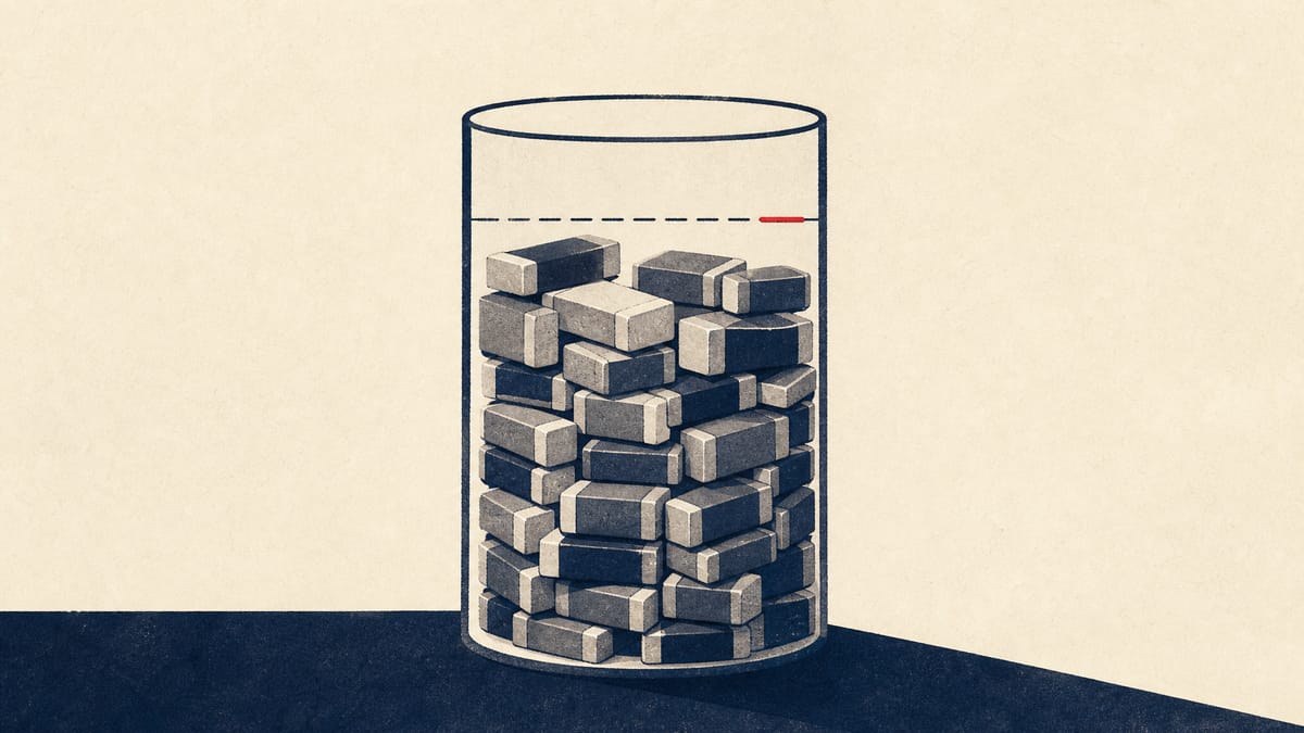 Stacked ceramic components filling a measuring vessel most of the way to a marked limit, illustrating progress against a spending ceiling
